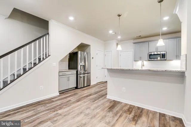 a kitchen with stainless steel appliances kitchen island granite countertop a refrigerator a stove and white cabinets with wooden floor