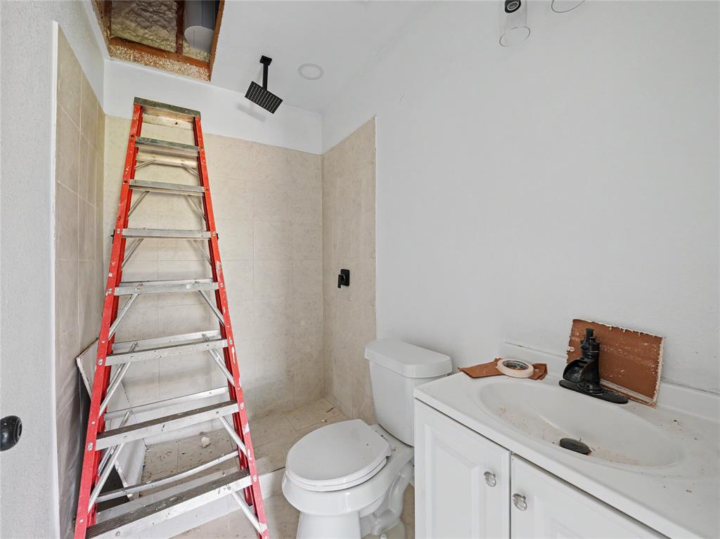 6701 Nauert Road Forest Hill, TX 76140 - Photo 36 of 40 Bathroom with a white vanity and integrated sink, a toilet, and light-toned wall tiling