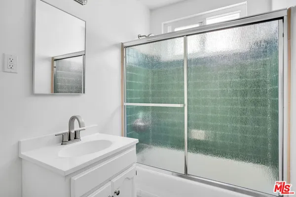 a bathroom with a shower sink and mirror