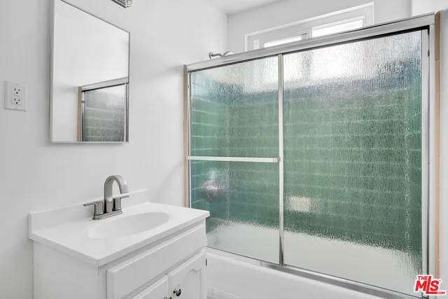 a bathroom with a shower sink and mirror