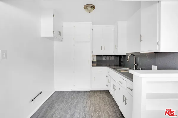a kitchen with stainless steel appliances granite countertop a stove a sink and white cabinets