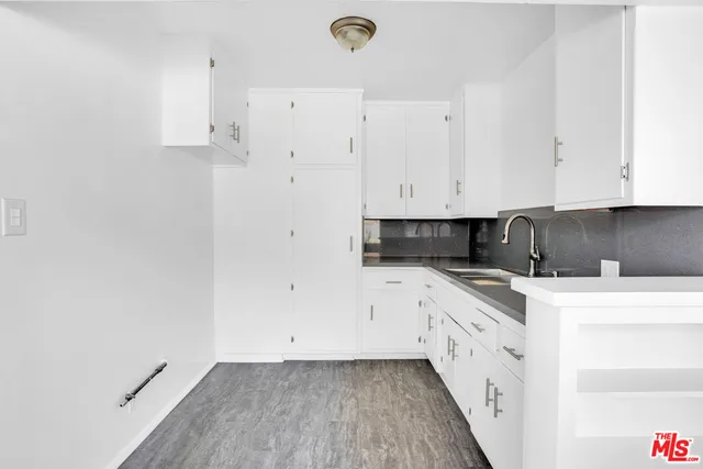 a kitchen with stainless steel appliances granite countertop a stove a sink and white cabinets