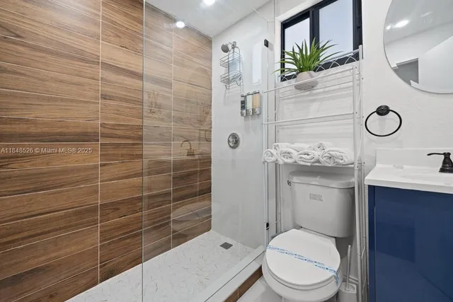 a bathroom with a granite countertop toilet sink and mirror
