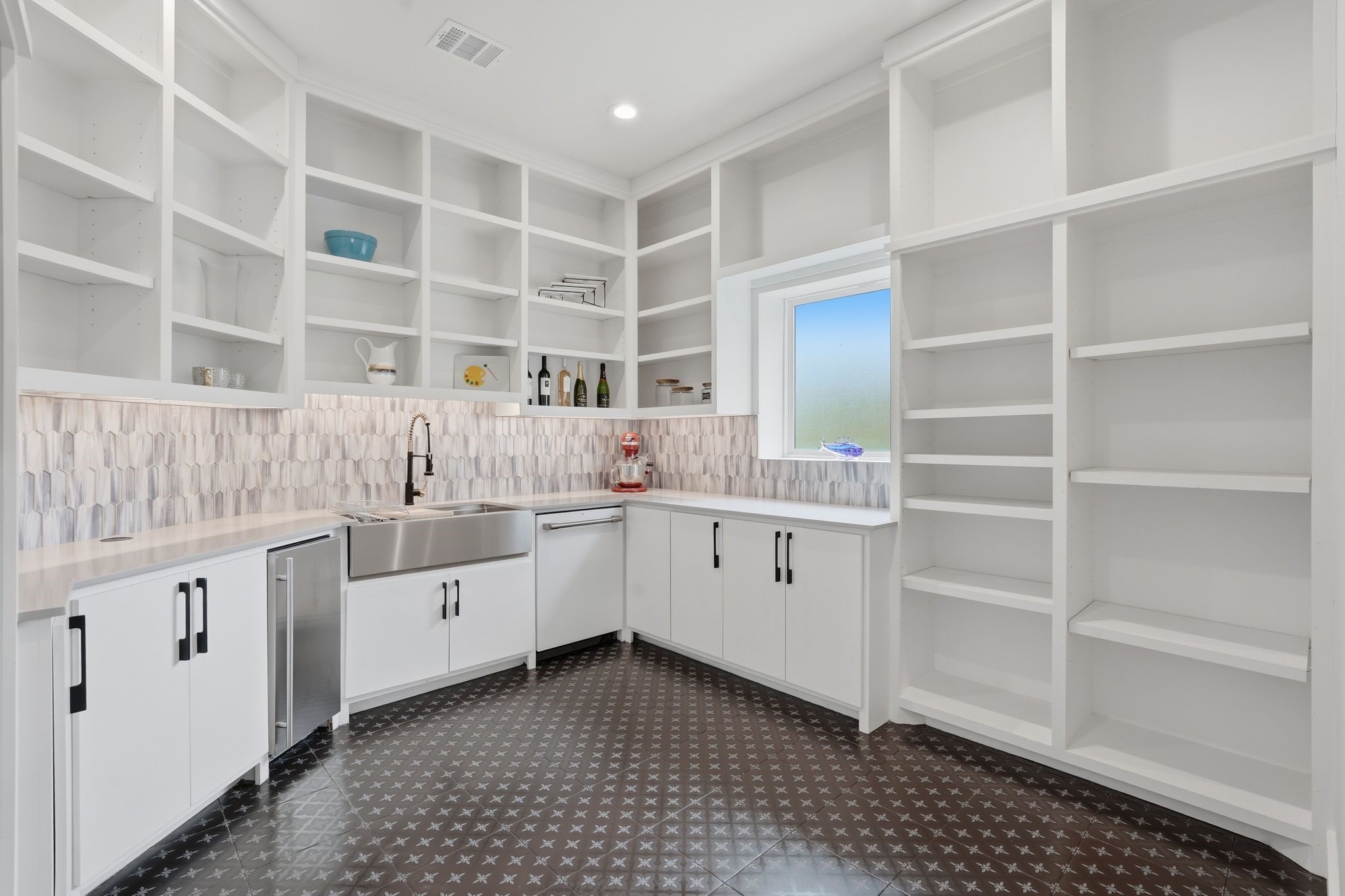 2743 Bobville Road Montgomery, TX 77316 - Photo 23 of 50 This is a bright, spacious walk-in butlers pantry with ample open shelving for storage, a modern farmhouse sink, stylish backsplash, and sleek cabinetry. The room features a patterned tile floor and a window for natural light, hidden behind the pantry doors in the main kitchen.