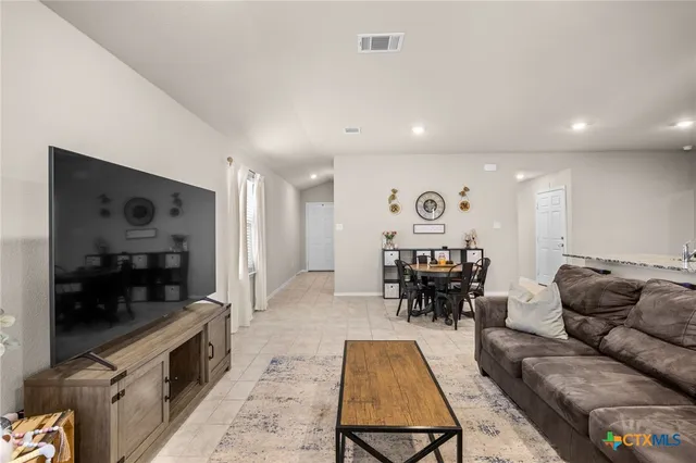 a living room with furniture and a flat screen tv with kitchen view