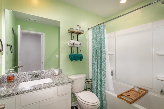 a bathroom with a granite countertop sink a toilet and shower