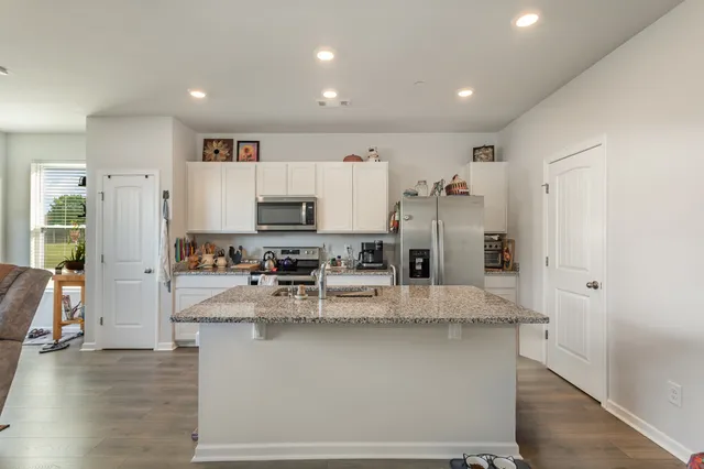 a view of a kitchen with kitchen island stainless steel appliances refrigerator sink and cabinets