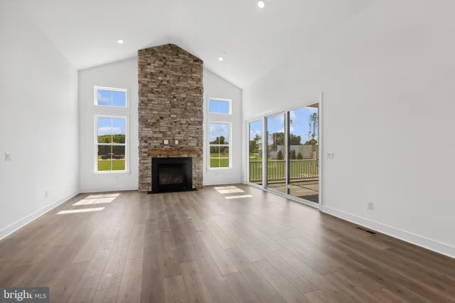 an empty room with wooden floor fireplace and windows
