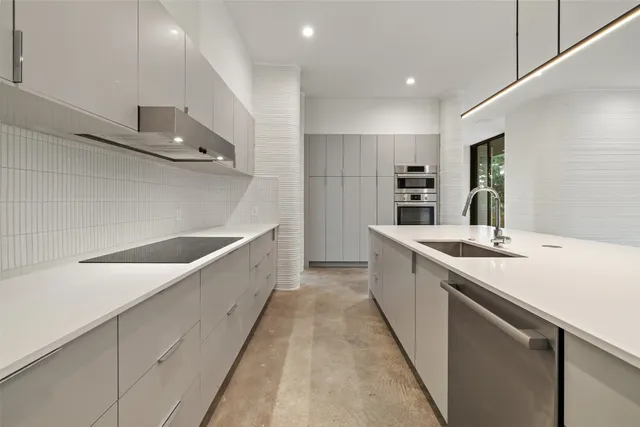a large white kitchen with a sink and stainless steel appliances