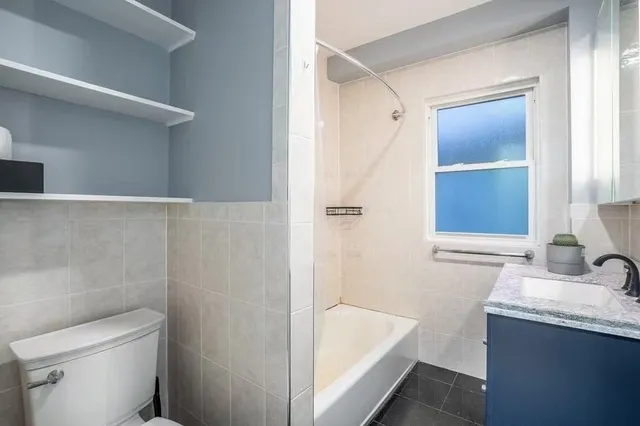 a bathroom with a granite countertop sink a toilet and shower