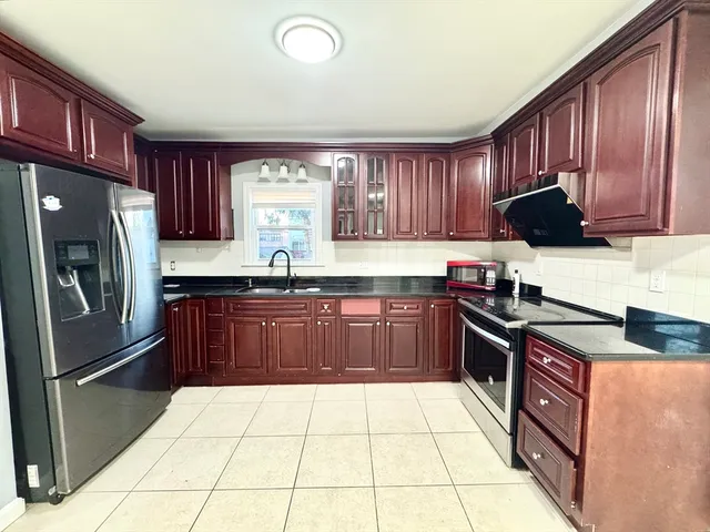a kitchen with granite countertop a refrigerator stove top oven and sink