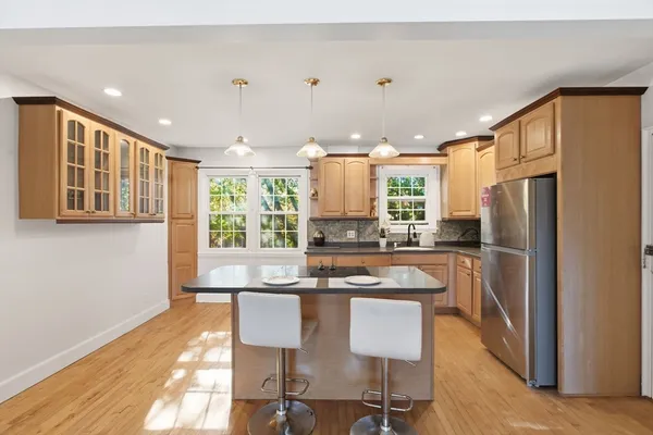 a kitchen with granite countertop a refrigerator a sink dishwasher a dining table and chairs with wooden floor