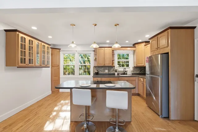 a kitchen with granite countertop a refrigerator a sink dishwasher a dining table and chairs with wooden floor