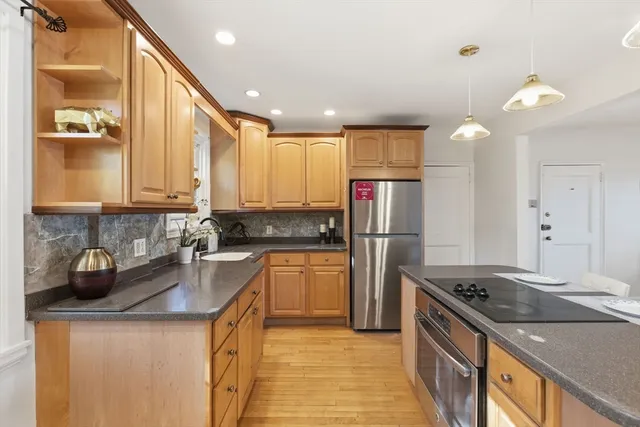 a kitchen with stainless steel appliances granite countertop a sink a stove and a refrigerator