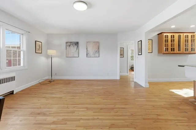 a view of an empty room with window and wooden floor
