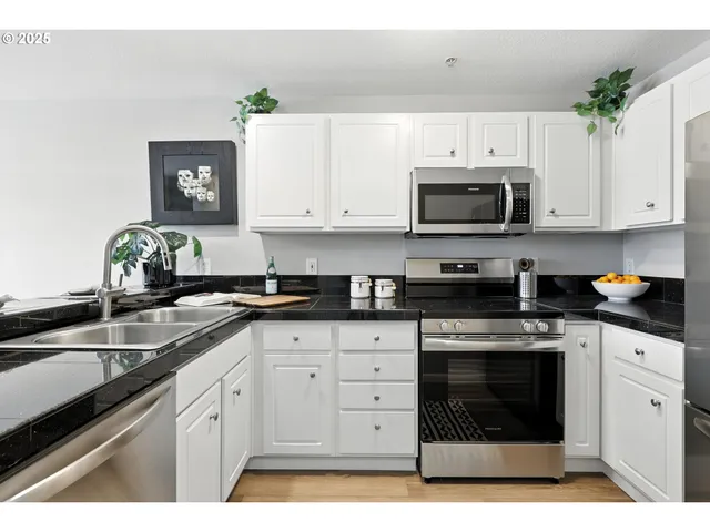 a kitchen with granite countertop white cabinets white stainless steel appliances and a sink