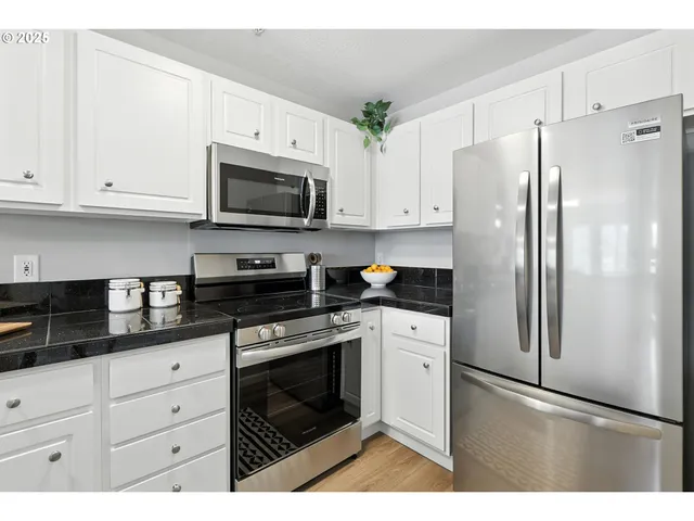 a kitchen with stainless steel appliances white cabinets and a refrigerator