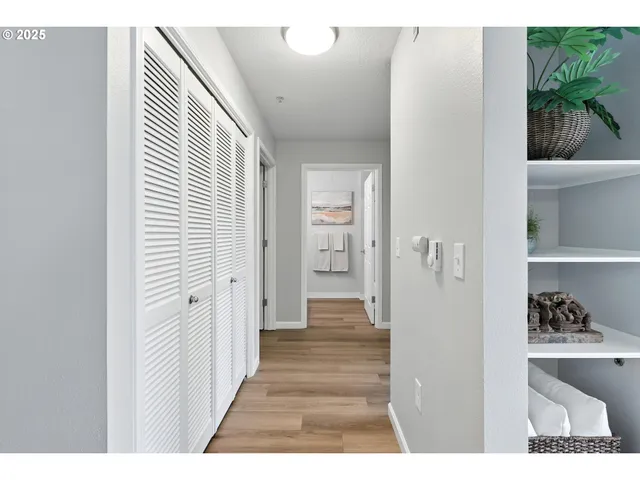 a view of a hallway with white cabinets and wooden floor