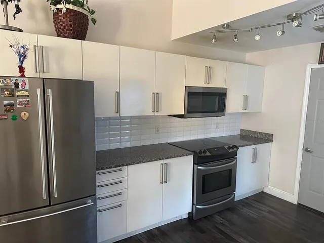 a kitchen with stainless steel appliances white cabinets and wooden floor