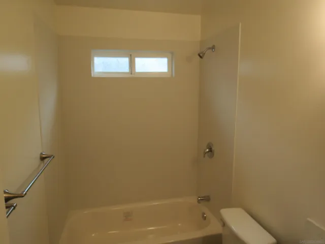 a bathroom with a granite countertop window a toilet and a bathtub