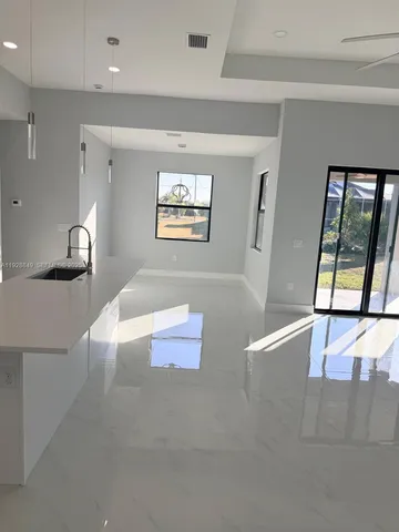 a living room with stainless steel appliances furniture a rug and a large window