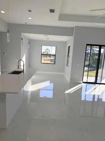 a living room with stainless steel appliances furniture a rug and a large window