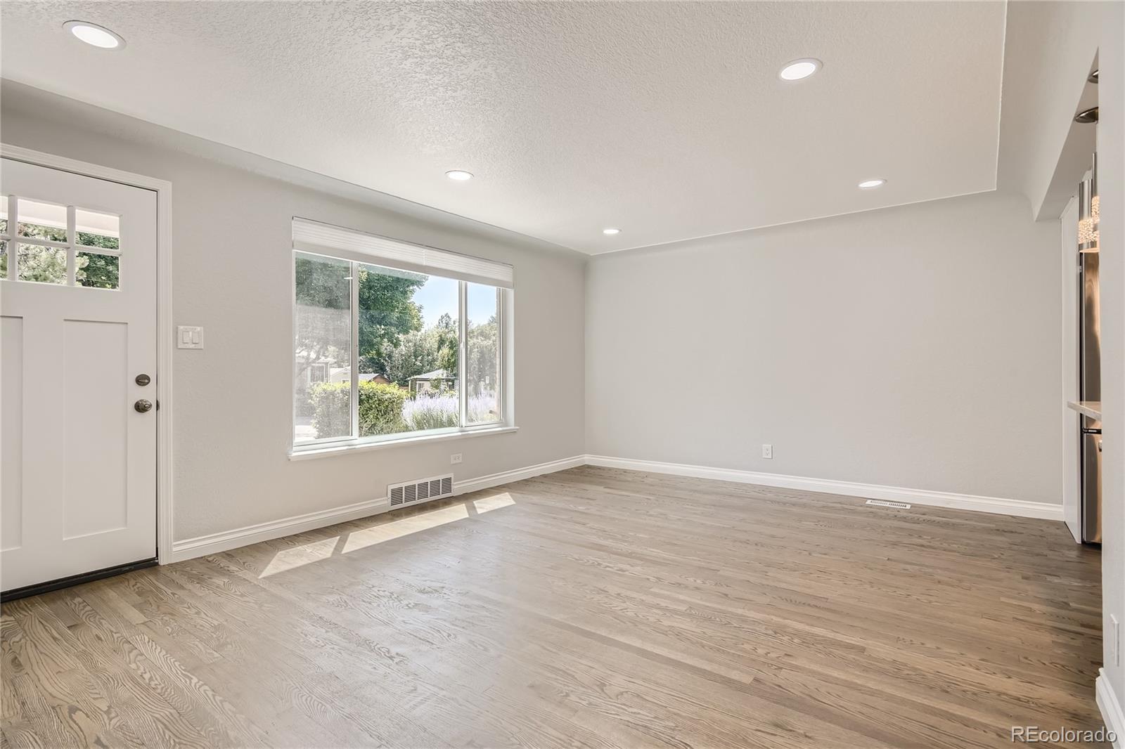 3485 Teller Street Wheat Ridge, CO 80033 - Photo 2 of 9 an empty room with wooden floor and windows