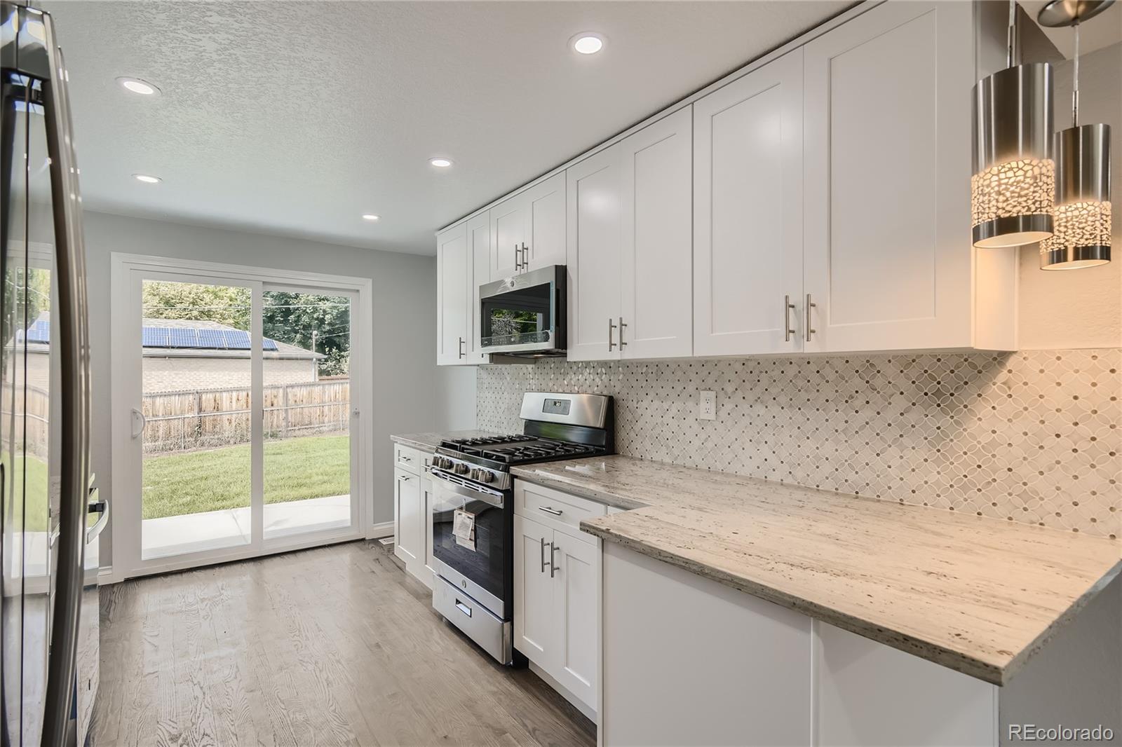 3485 Teller Street Wheat Ridge, CO 80033 - Photo 3 of 9 a kitchen with stainless steel appliances granite countertop a stove a sink and a white cabinets