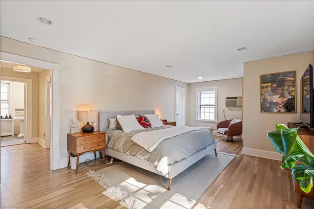 a view of a hallway with wooden floor and a bathroom