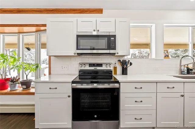 a kitchen with white cabinets and appliances