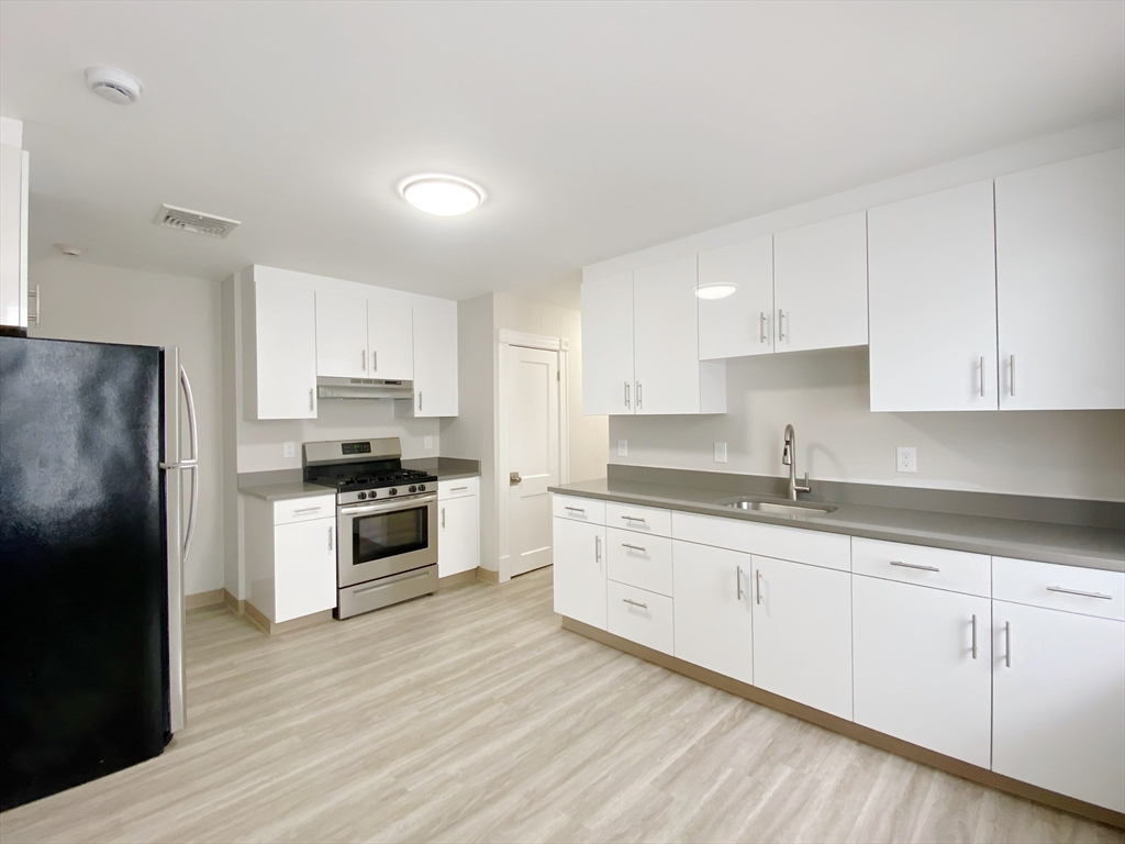 a kitchen with granite countertop white cabinets and stainless steel appliances