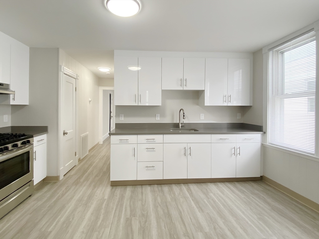44 Jones Road, Unit 5 Revere, MA 02151 - Photo 5 of 11 a kitchen with granite countertop white cabinets and white appliances
