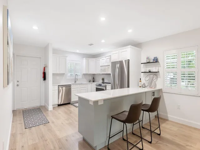 a living room with stainless steel appliances furniture a refrigerator and a kitchen view