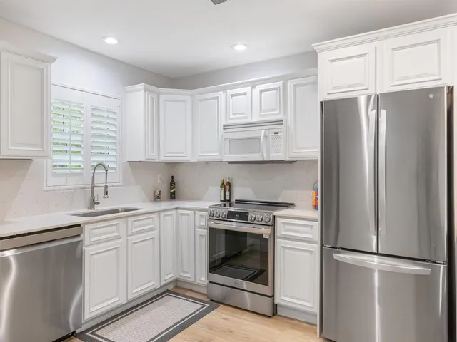 a kitchen with stainless steel appliances a sink a stove and white cabinets
