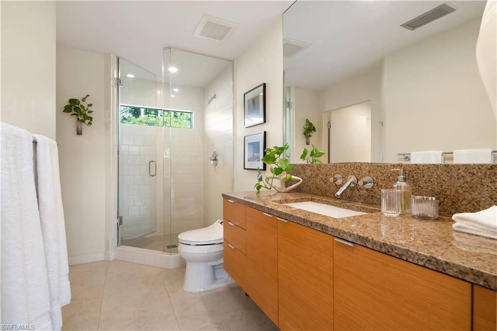 705 Shadow Lake Lane Naples, FL 34108 - Photo 35 of 47 a bathroom with a granite countertop sink a toilet a mirror and shower