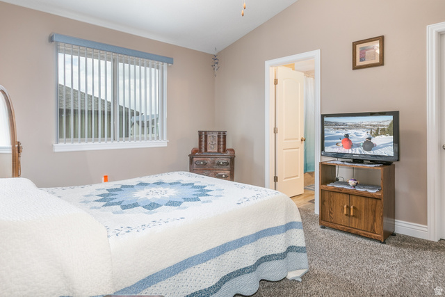 1228 North Providence Way Tooele, UT 84074 - Photo 13 of 28 Bedroom featuring vaulted ceilings, light tan wall paint, vertical window blinds, and carpet flooring