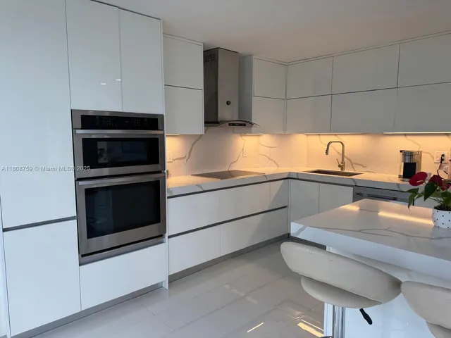 a kitchen with granite countertop white cabinets and stainless steel appliances