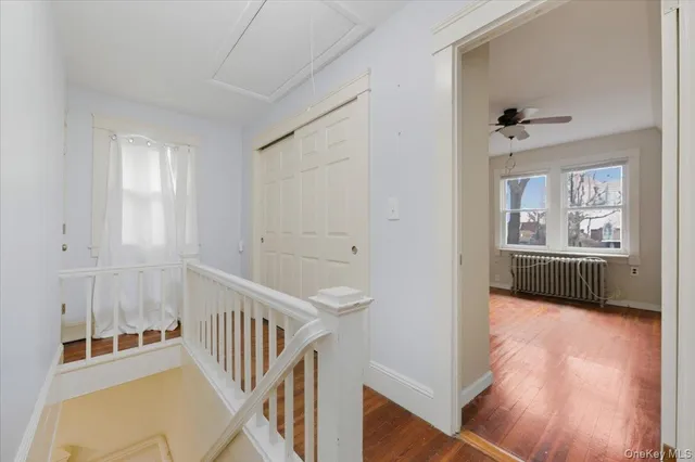 a view of a hallway with wooden floor and a kitchen