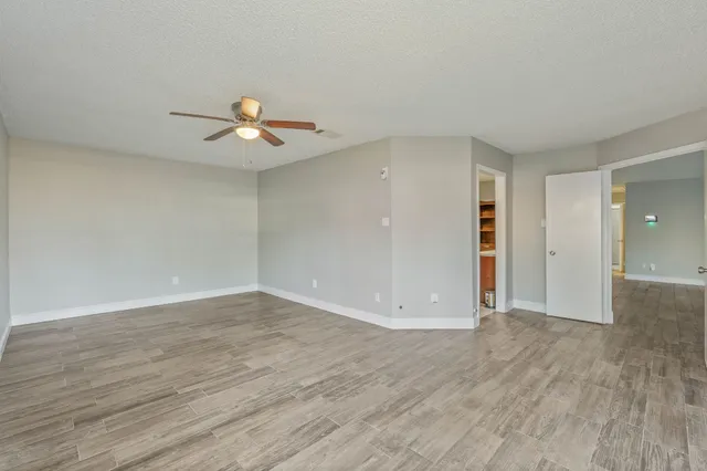 an empty room with wooden floor and ceiling fan