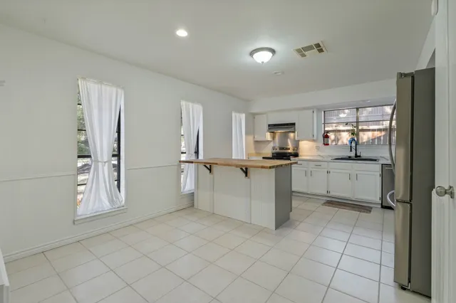 a kitchen with white cabinets and refrigerator