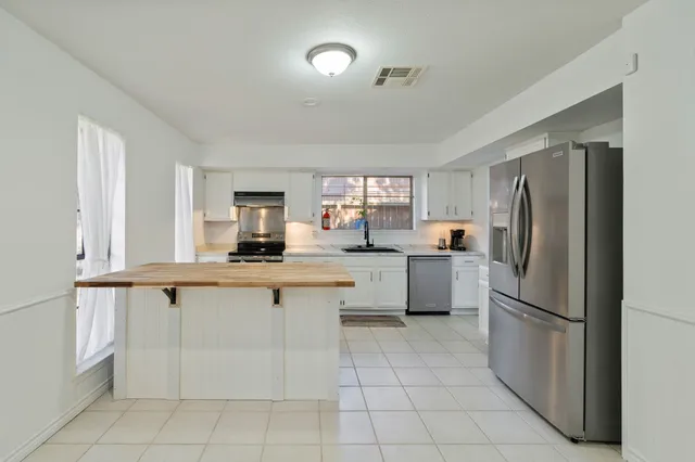 a kitchen with a refrigerator and white cabinets