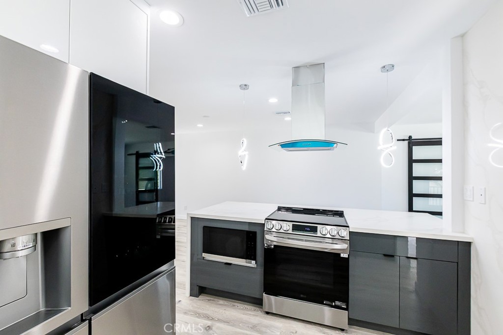 6160 Shoshone Avenue Encino, CA 91316 - Photo 11 of 22 a kitchen with stainless steel appliances kitchen island a stove and a refrigerator
