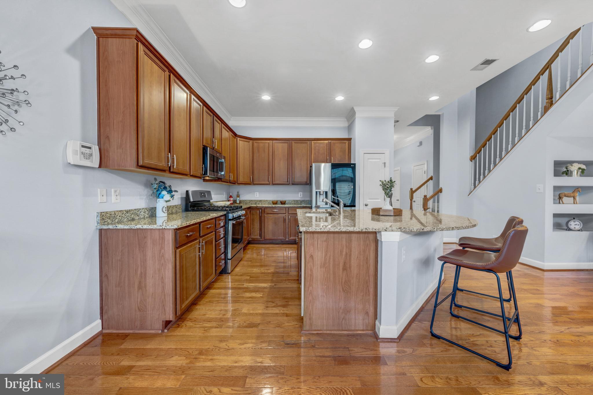 9231 Ribbon Falls Loop Bristow, VA 20136 - Photo 12 of 40 a kitchen with stainless steel appliances granite countertop a stove top oven a sink dishwasher and cabinets with wooden floor