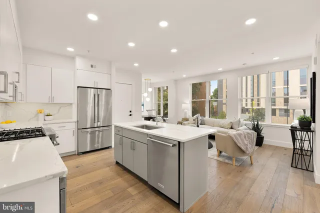 a kitchen with a sink a stove a refrigerator and white cabinets with wooden floor