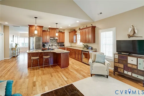 a living room with stainless steel appliances furniture and a flat screen tv