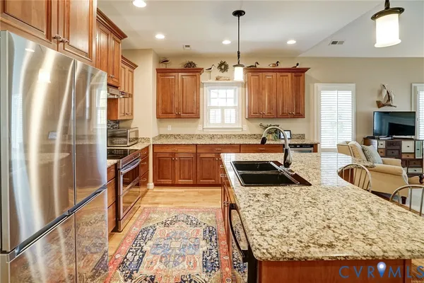 a kitchen with stainless steel appliances kitchen island granite countertop a sink stove and refrigerator