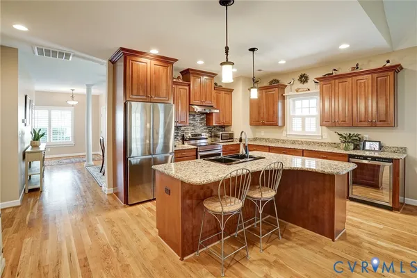 a kitchen with stainless steel appliances granite countertop wooden floors stove top oven and refrigerator
