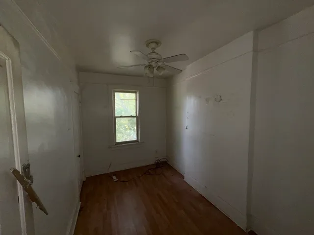 an empty room with a window and a fan