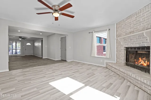 an empty room with windows and fireplace