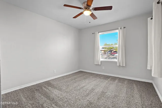 an empty room with a window and a ceiling fan